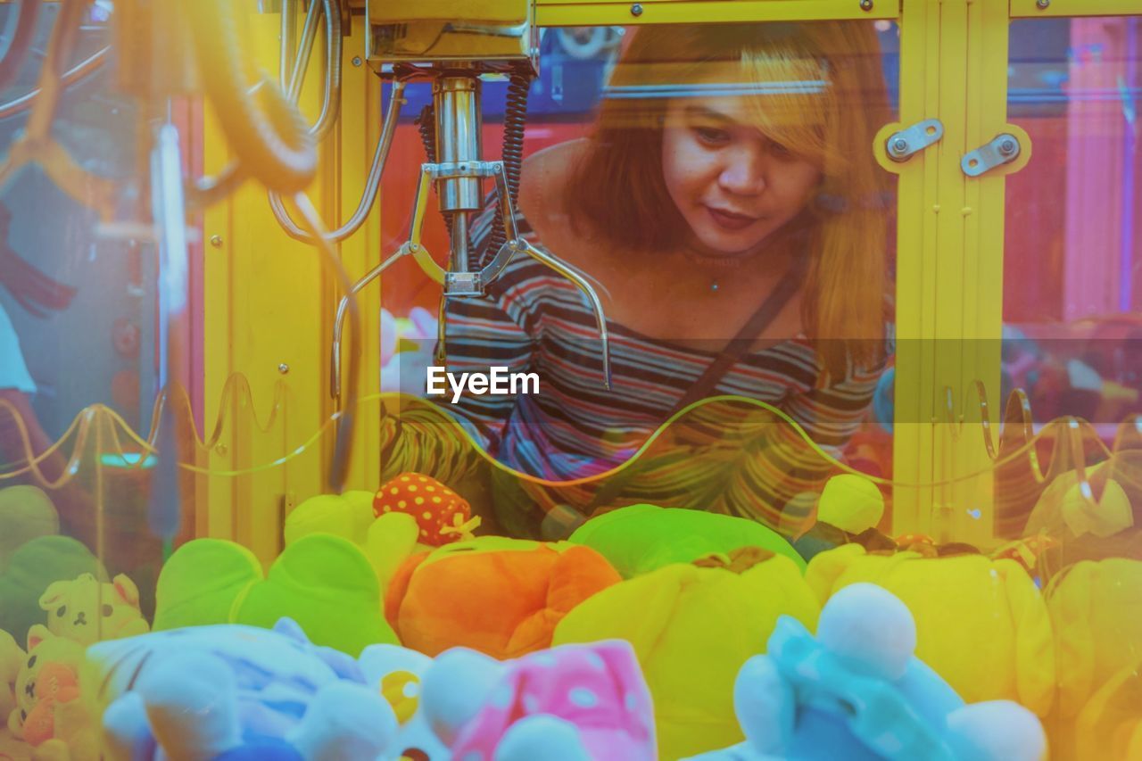 Portrait of smiling young woman looking at the claw machine