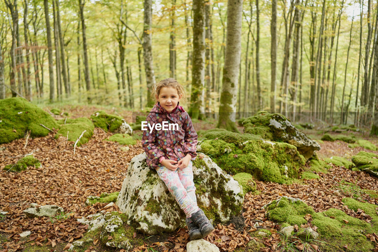 Joyful small kid in warm clothes looking at camera and smiling while s
