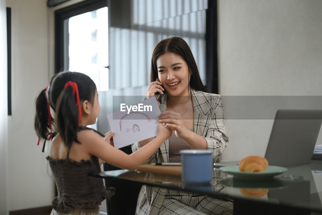 female friends using mobile phone while sitting on table