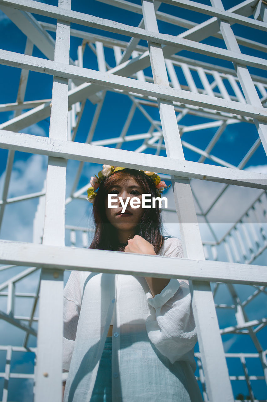 Portrait of woman standing by metallic built structure