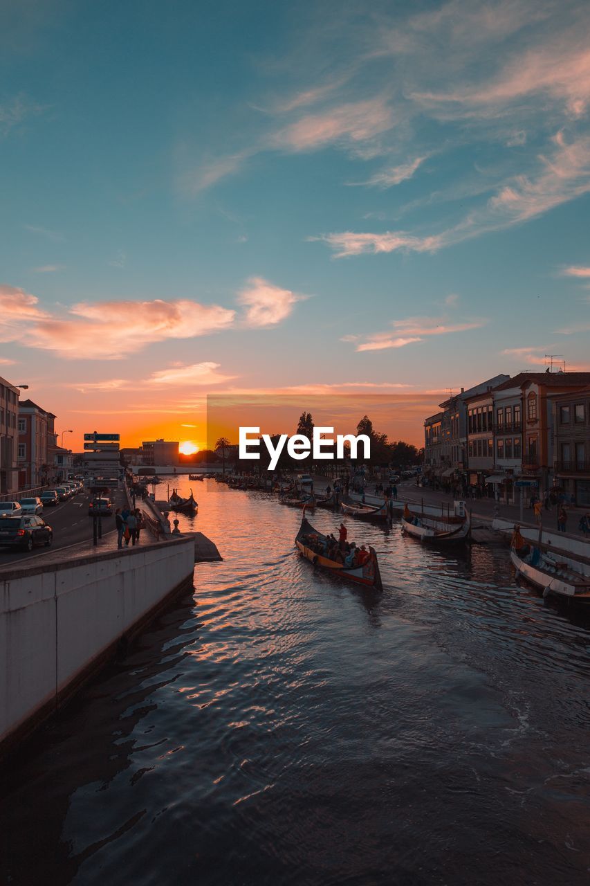 Boats moored in river against sky during sunset