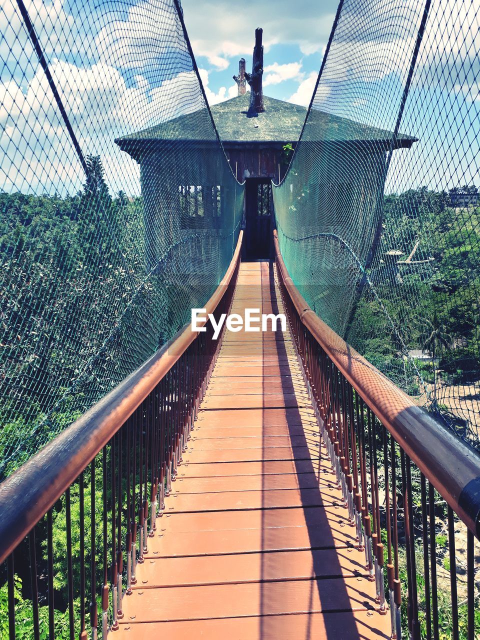 Footbridge amidst trees against sky