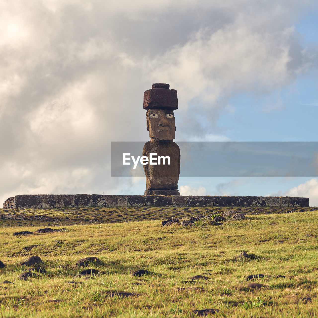 Stack of moai statues on field against sky