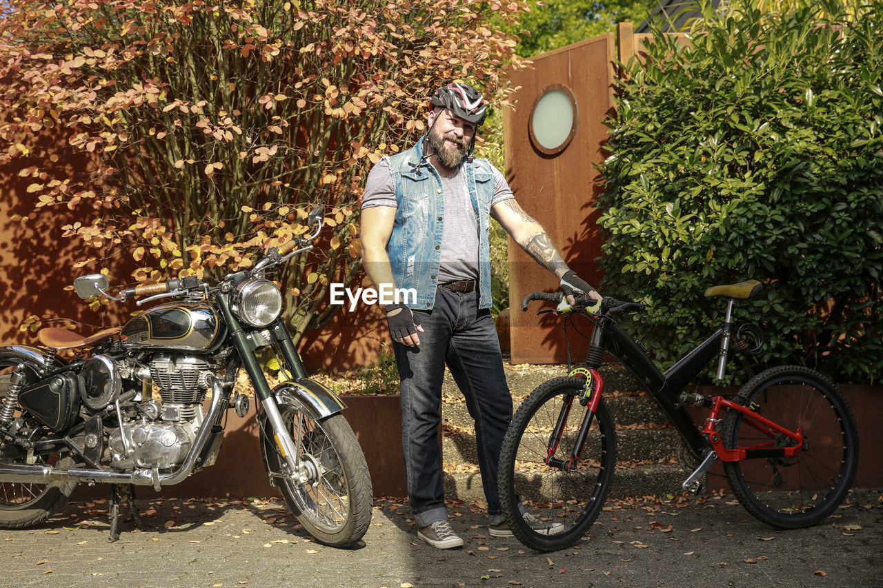 Portrait of man switching from motorbike to bicycle