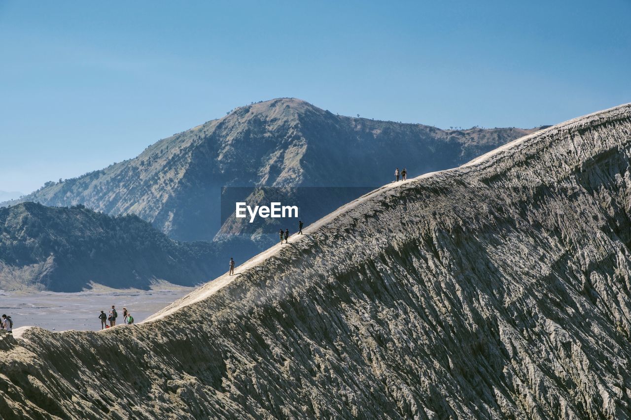 Scenic view of hikers on mountains against clear sky