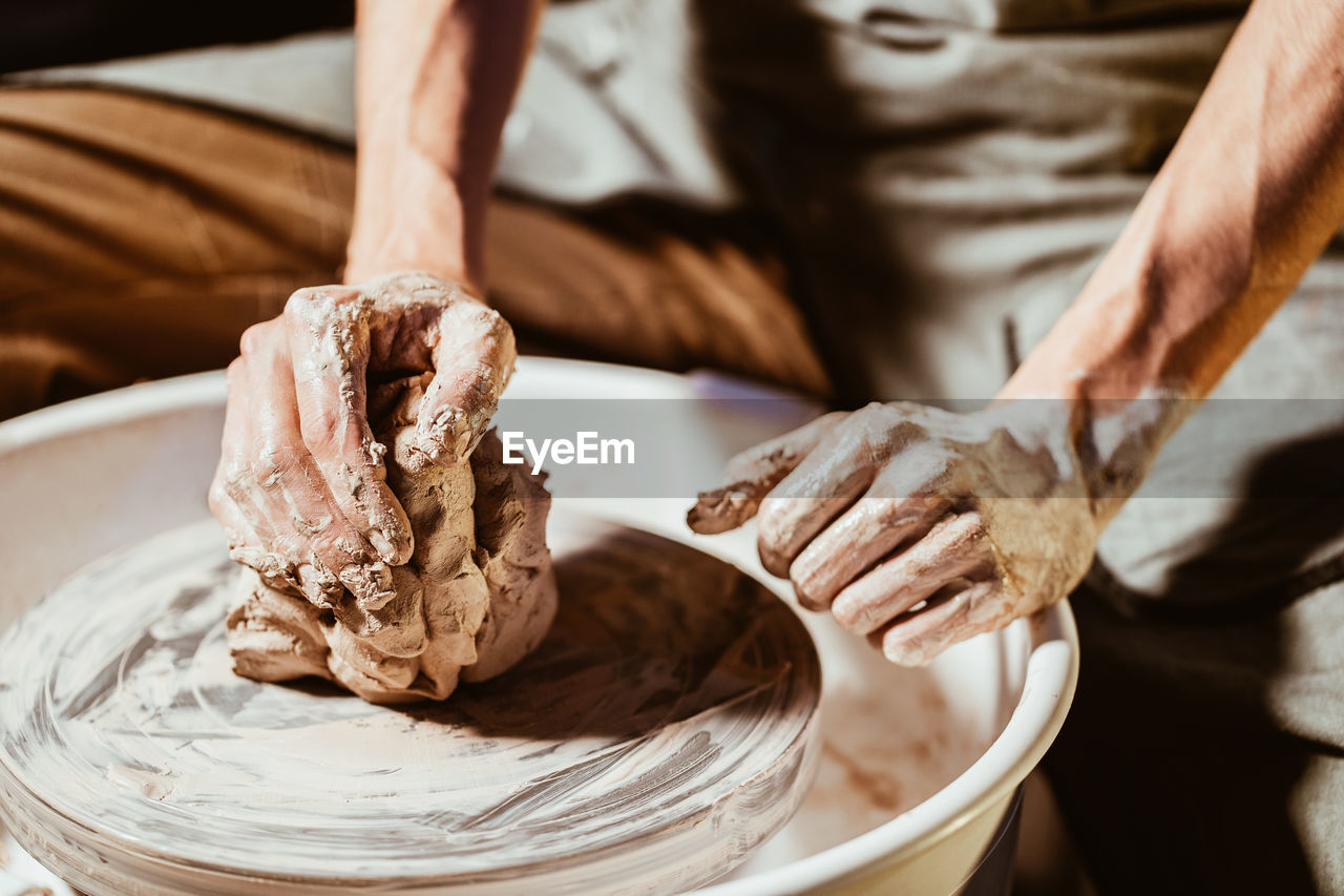 Cropped hands of potter making pot in pottery workshop