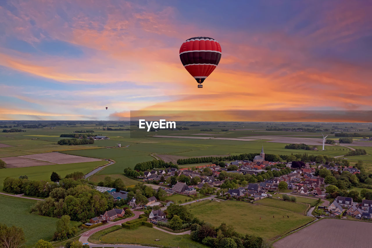 Aerial from a flying hot air balloon in the countryside from the netherlands at sunset