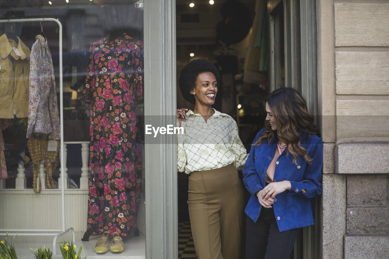 Female entrepreneurs laughing while talking with each other at clothing store