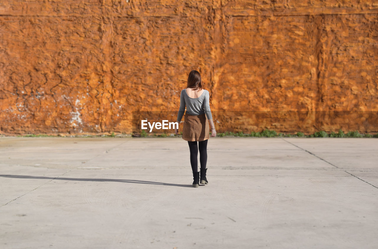 Rear view of woman walking towards wall