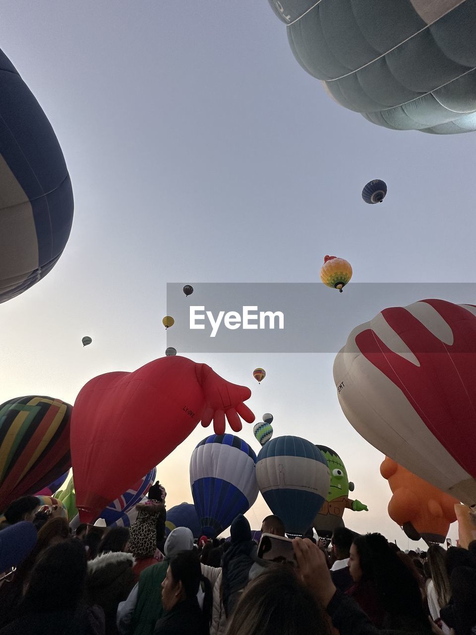hot air balloon, balloon, mid-air, flying, vehicle, air vehicle, aircraft, hot air ballooning, low angle view, nature, sky, toy, day, multi colored, outdoors, group of people, transportation, large group of objects