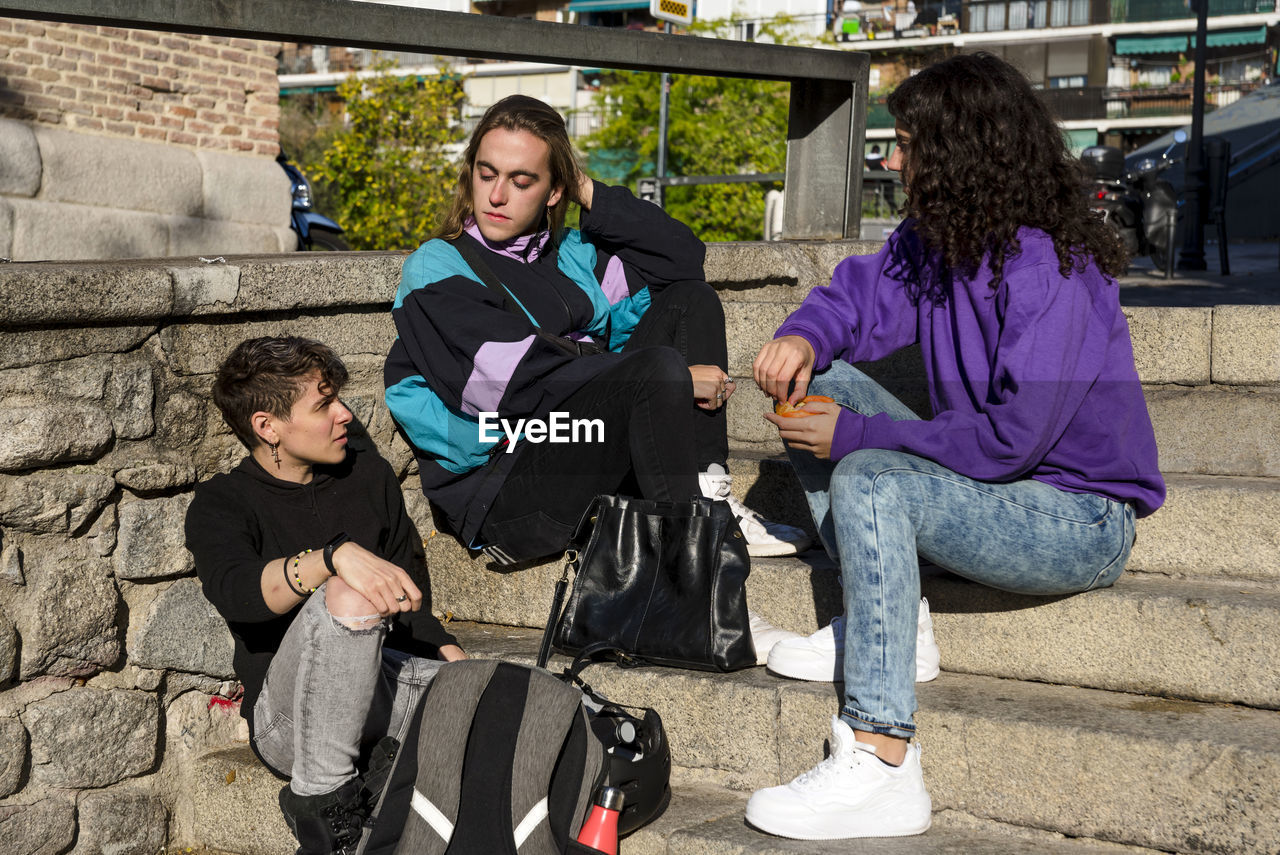 Friends talking while standing outdoors on the street.