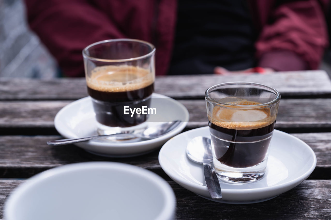 CLOSE-UP OF COFFEE CUP AND GLASS ON TABLE