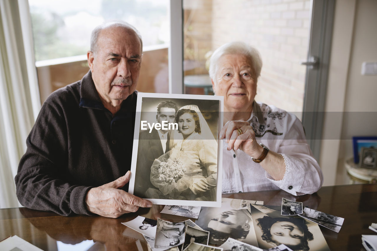 Senior couple showing their wedding photo at home