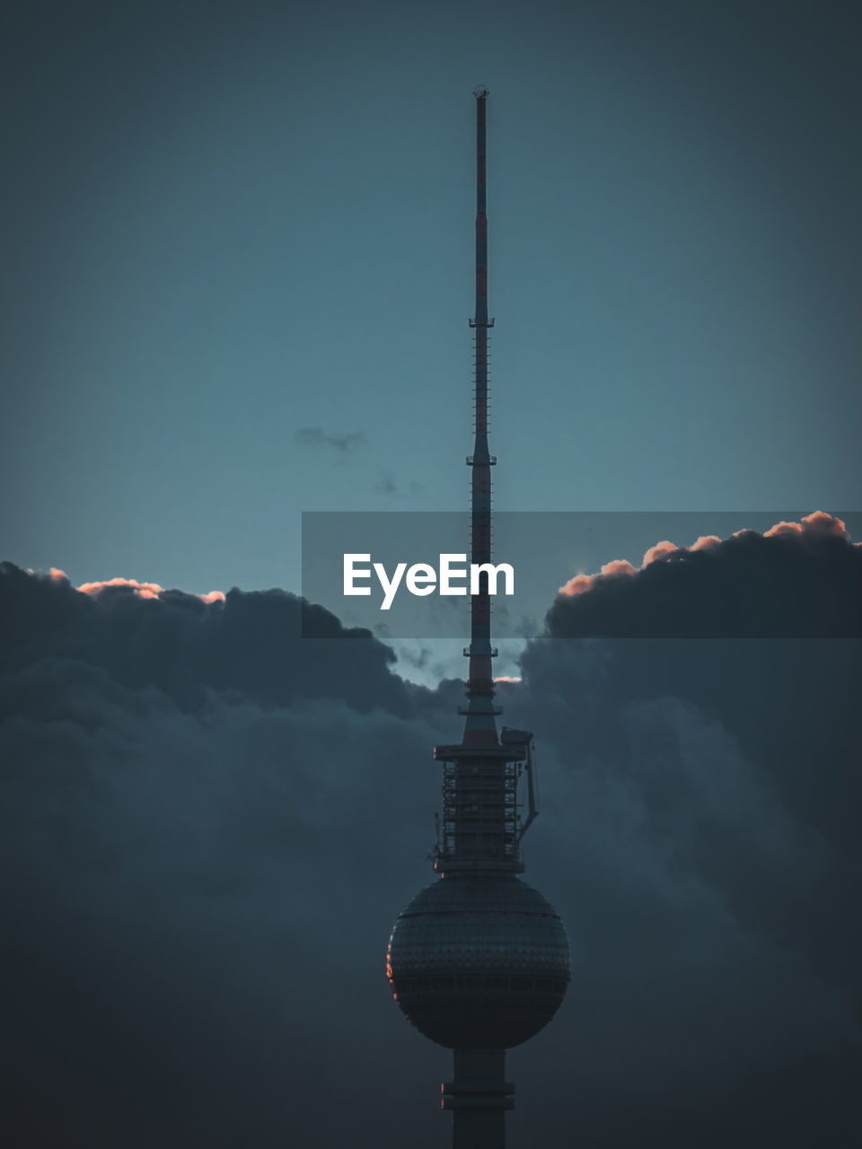 Silhouette communications tower against cloudy sky during sunset
