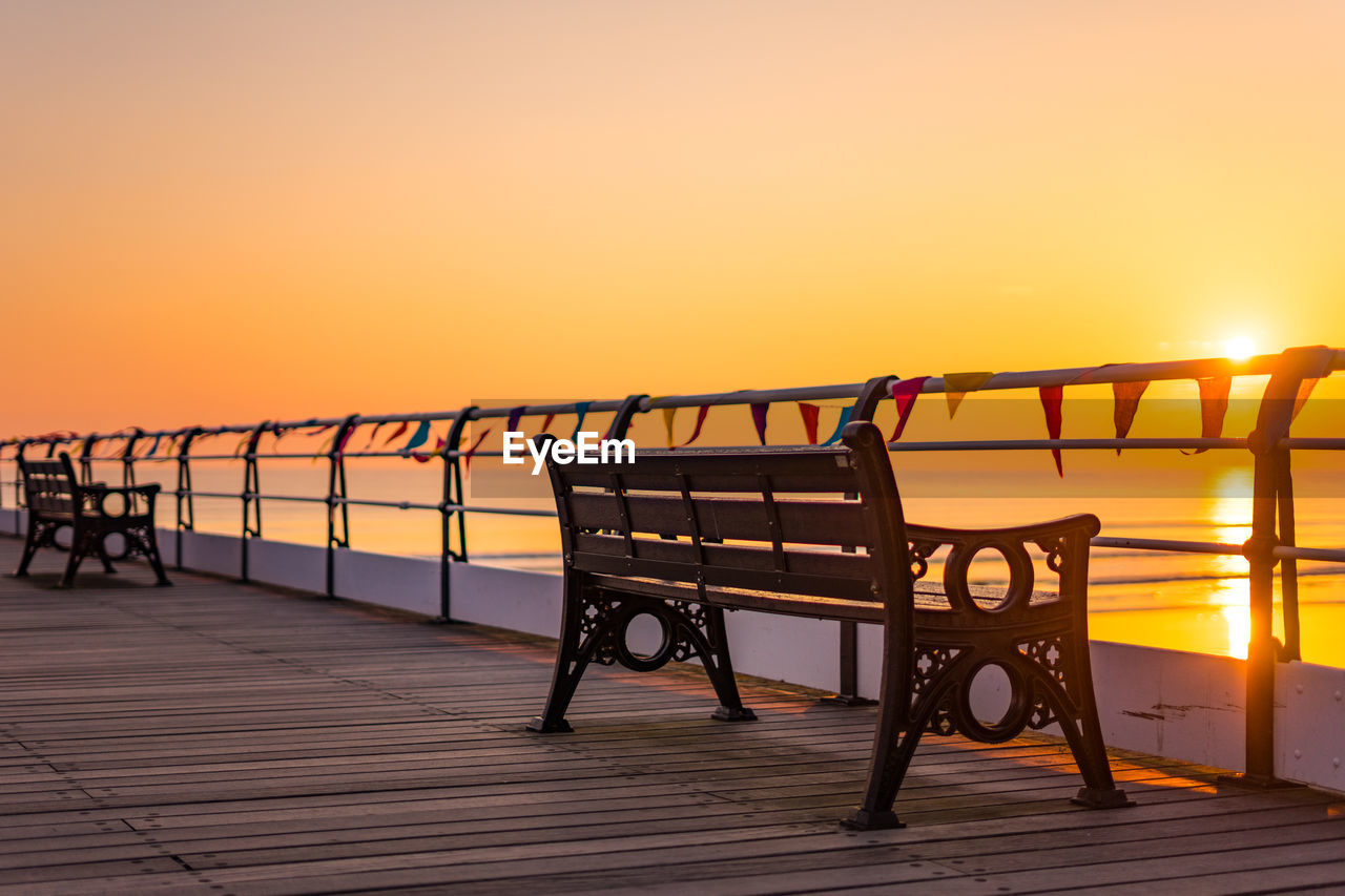 EMPTY BENCHES AGAINST ORANGE SKY