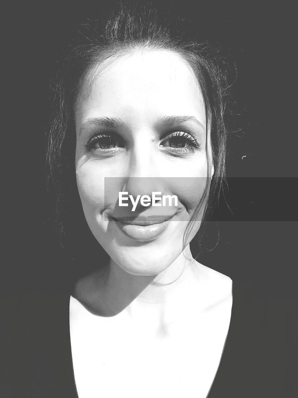 Close-up portrait of smiling woman over black background