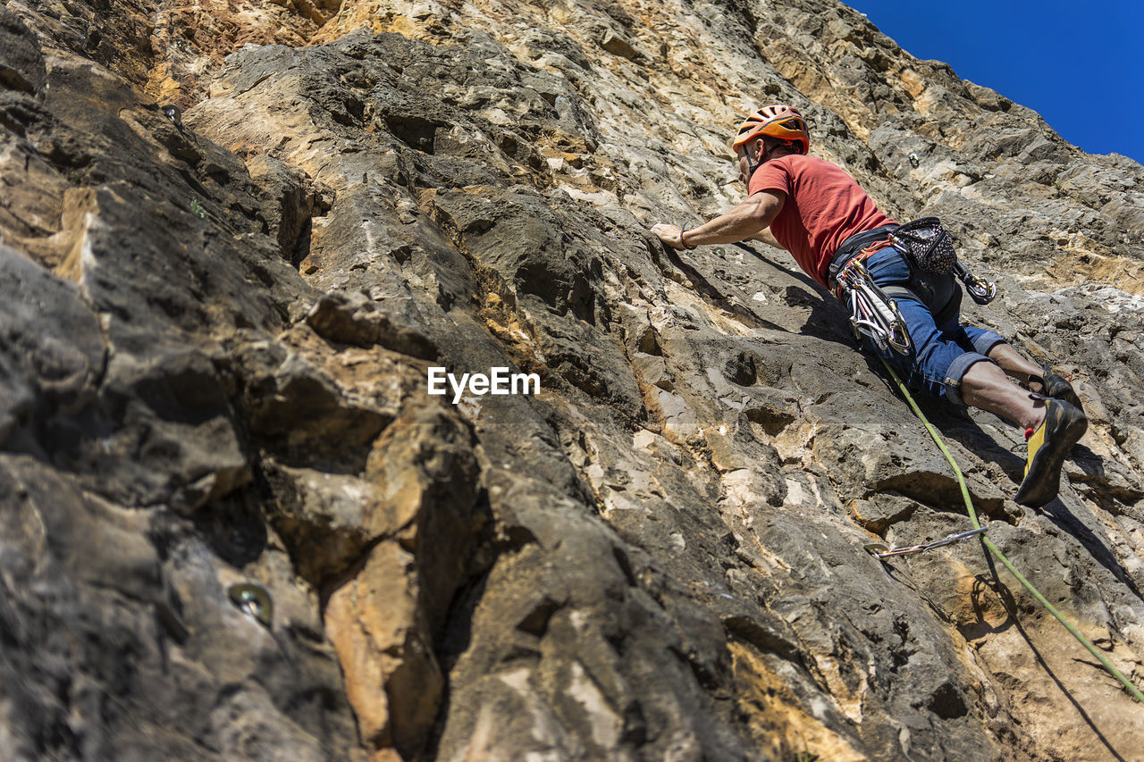 Low angle view of man climbing rock