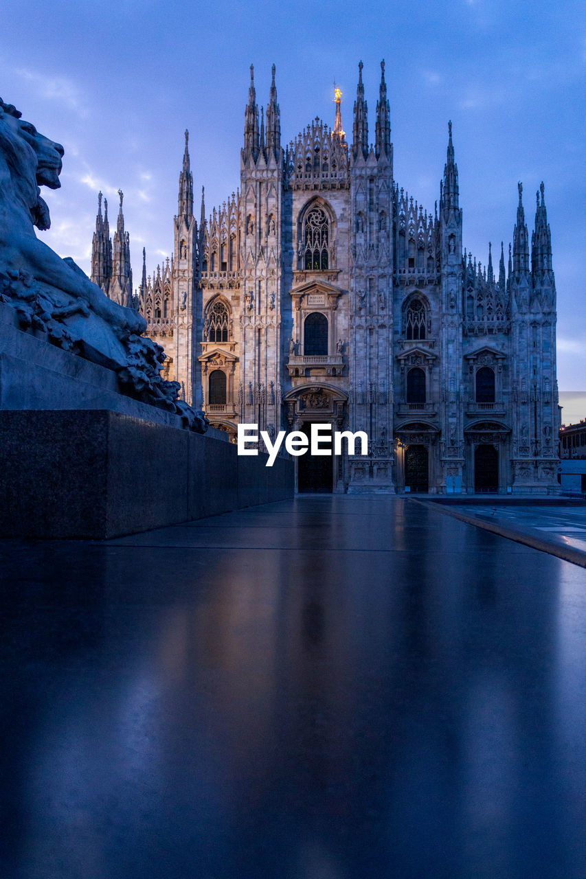 Dark architecture image of the duomo cathedral in milano italy. view with the lion statue