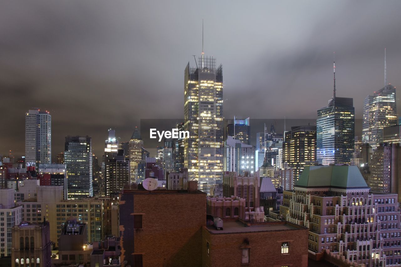 Illuminated buildings in city against sky