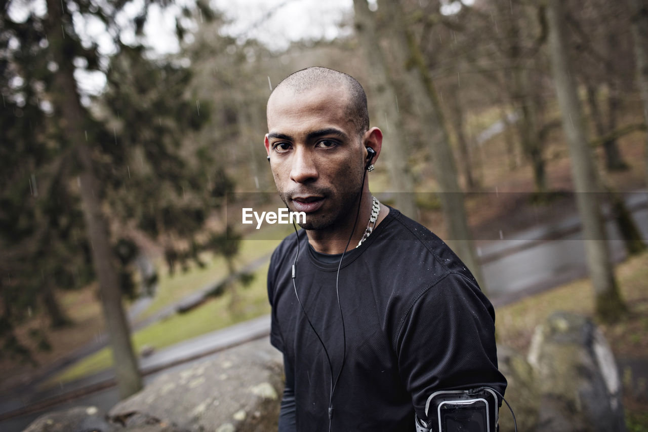 Portrait of confident male athlete standing in forest