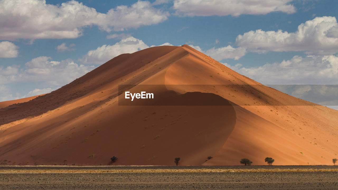 Scenic view of desert against cloudy sky