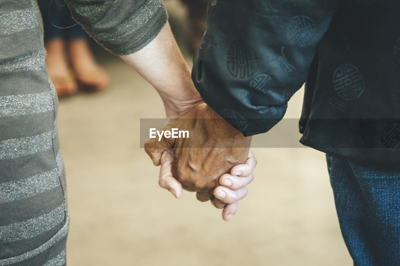 Midsection of couple holding hands