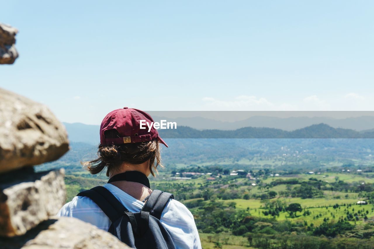 REAR VIEW OF WOMAN ON LANDSCAPE AGAINST MOUNTAIN