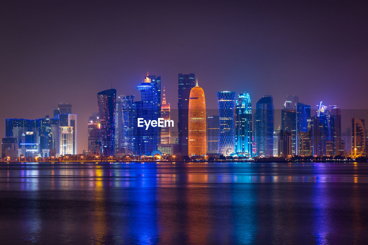 Coloful illuminated skyline of doha at night, qatar, middle east against dark sky