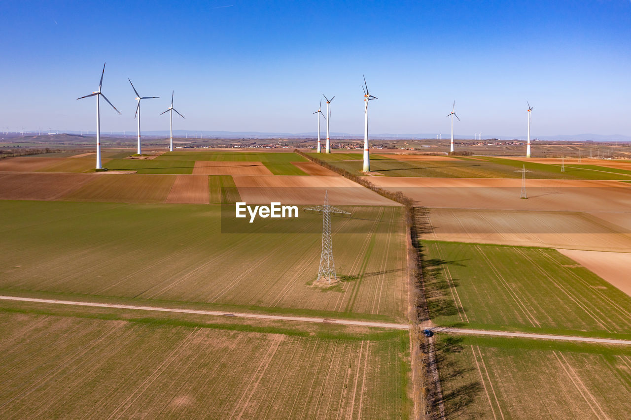 A power pole and many huge wind turbines on a field seen from above as a drone shot, energiewende