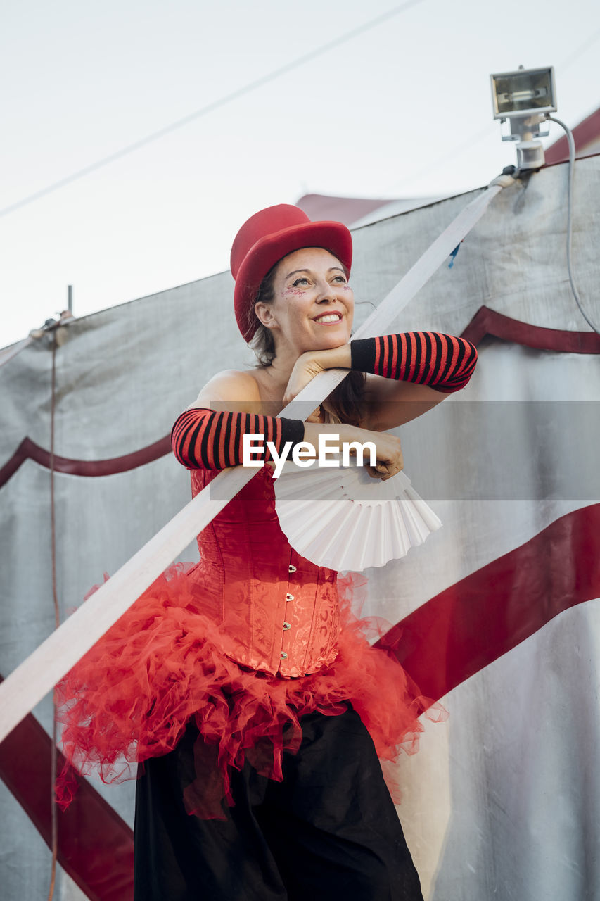 Female artist looking away while standing by circus tent