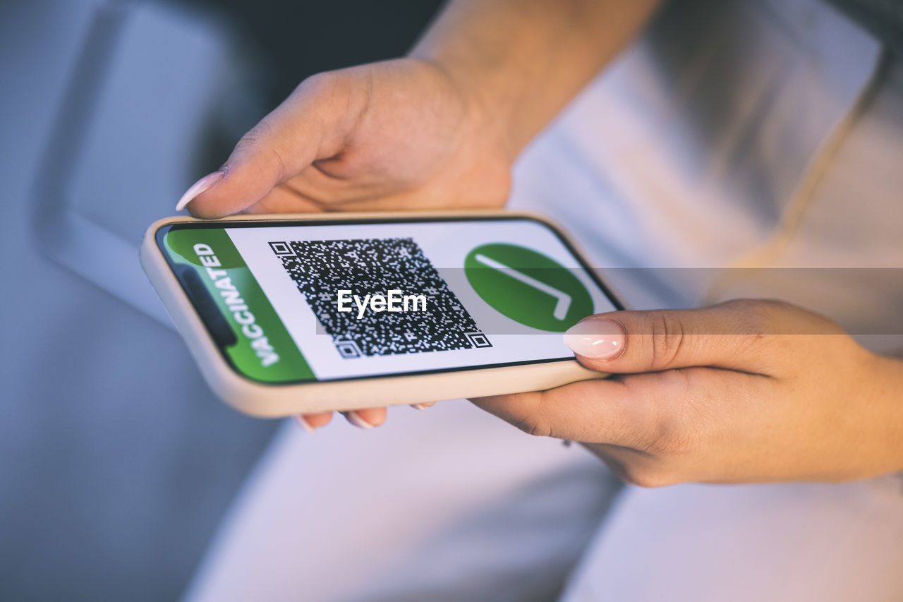 Woman holding mobile phone with covid-19 qr code on screen