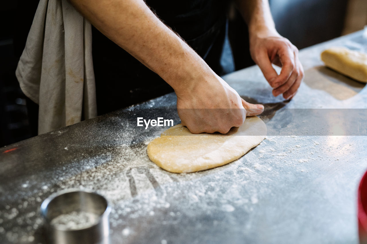 MIDSECTION OF MAN PREPARING FOOD AT TABLE