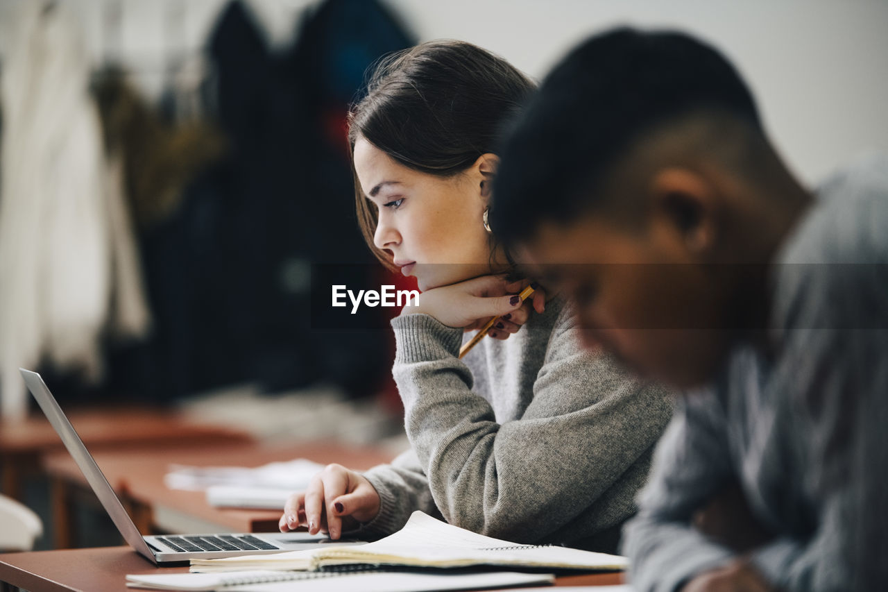 Teenage students studying at desk in classroom