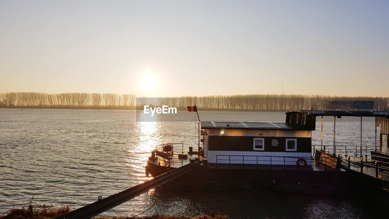 BOATS SAILING IN LAKE AGAINST CLEAR SKY DURING SUNSET