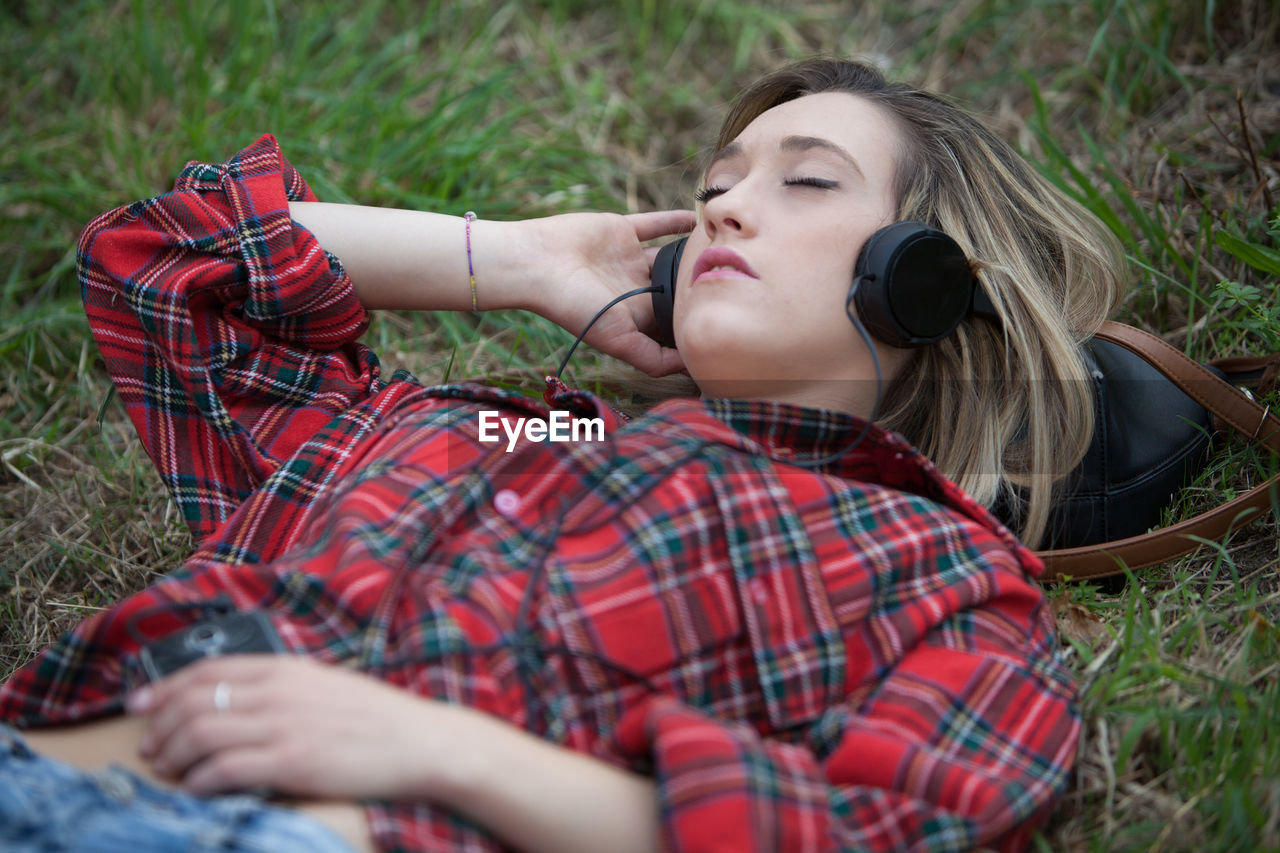 High angle view of woman listening music while lying on field