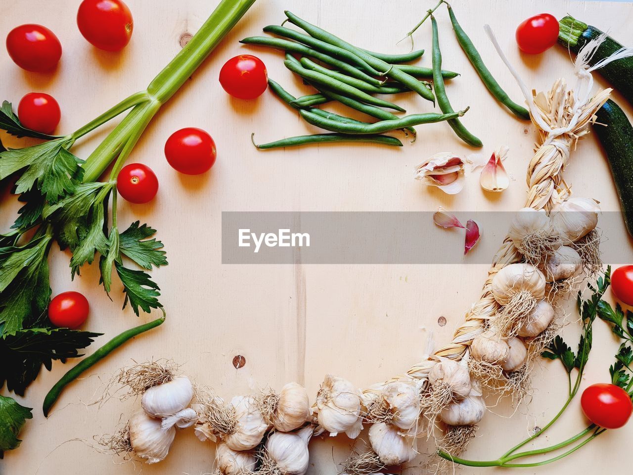 Flat lay with garlic braid and vegetables on wooden cutting board