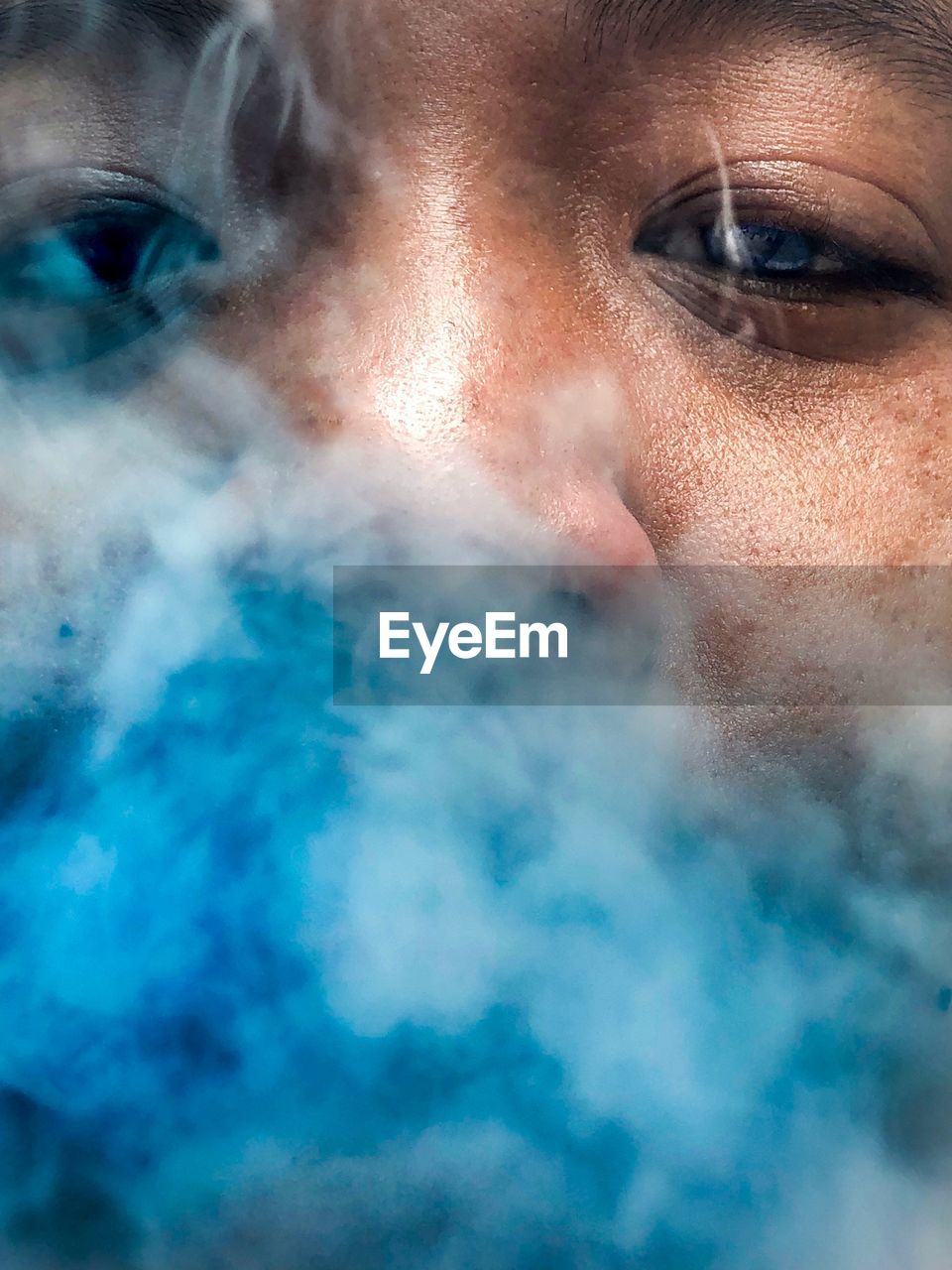 Close-up portrait of man amidst blue smoke