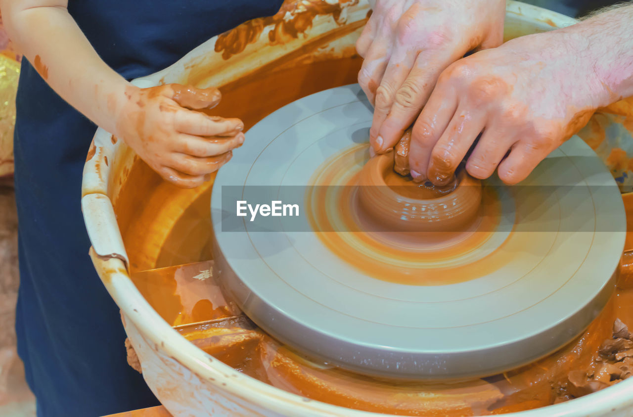 Girl and man making mud product on pottery wheel