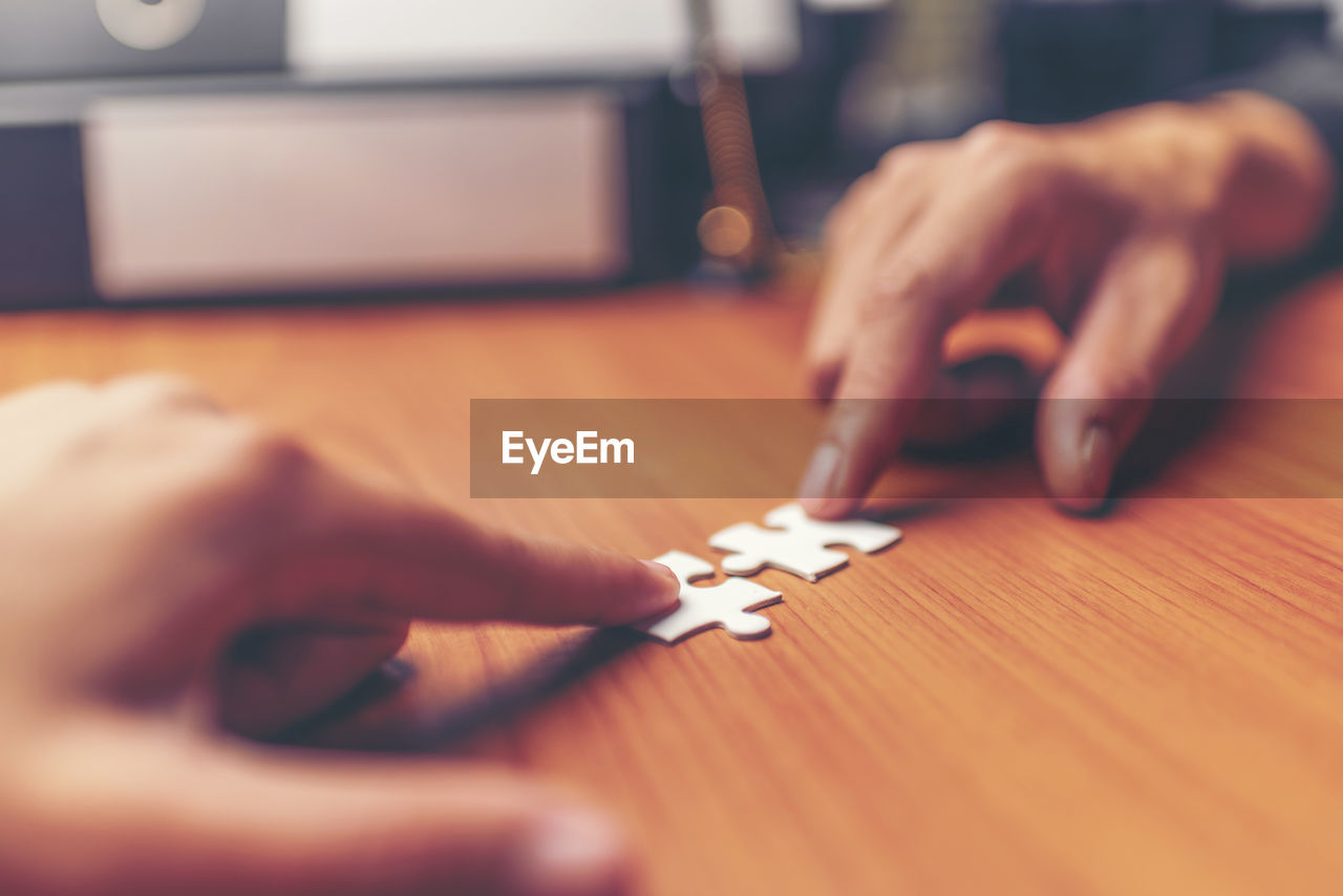 Close-up of hands playing jigsaw puzzle on table