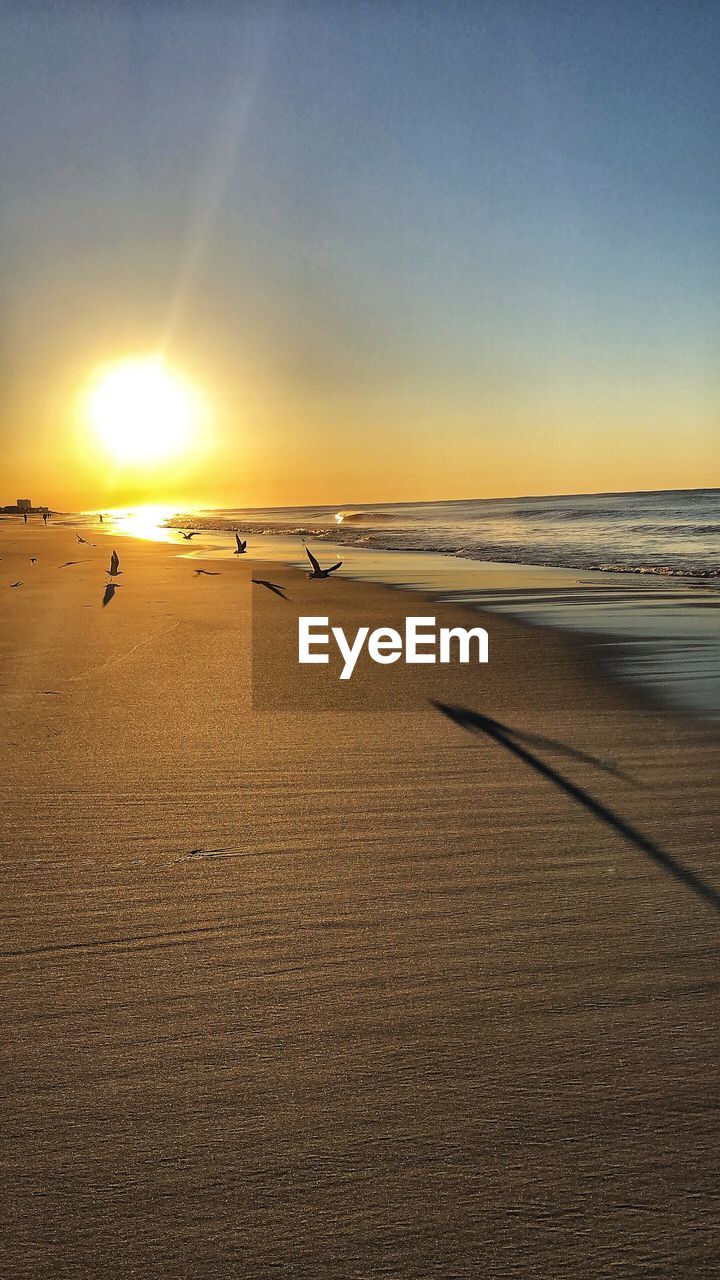 SCENIC VIEW OF BEACH AGAINST SKY AT SUNSET