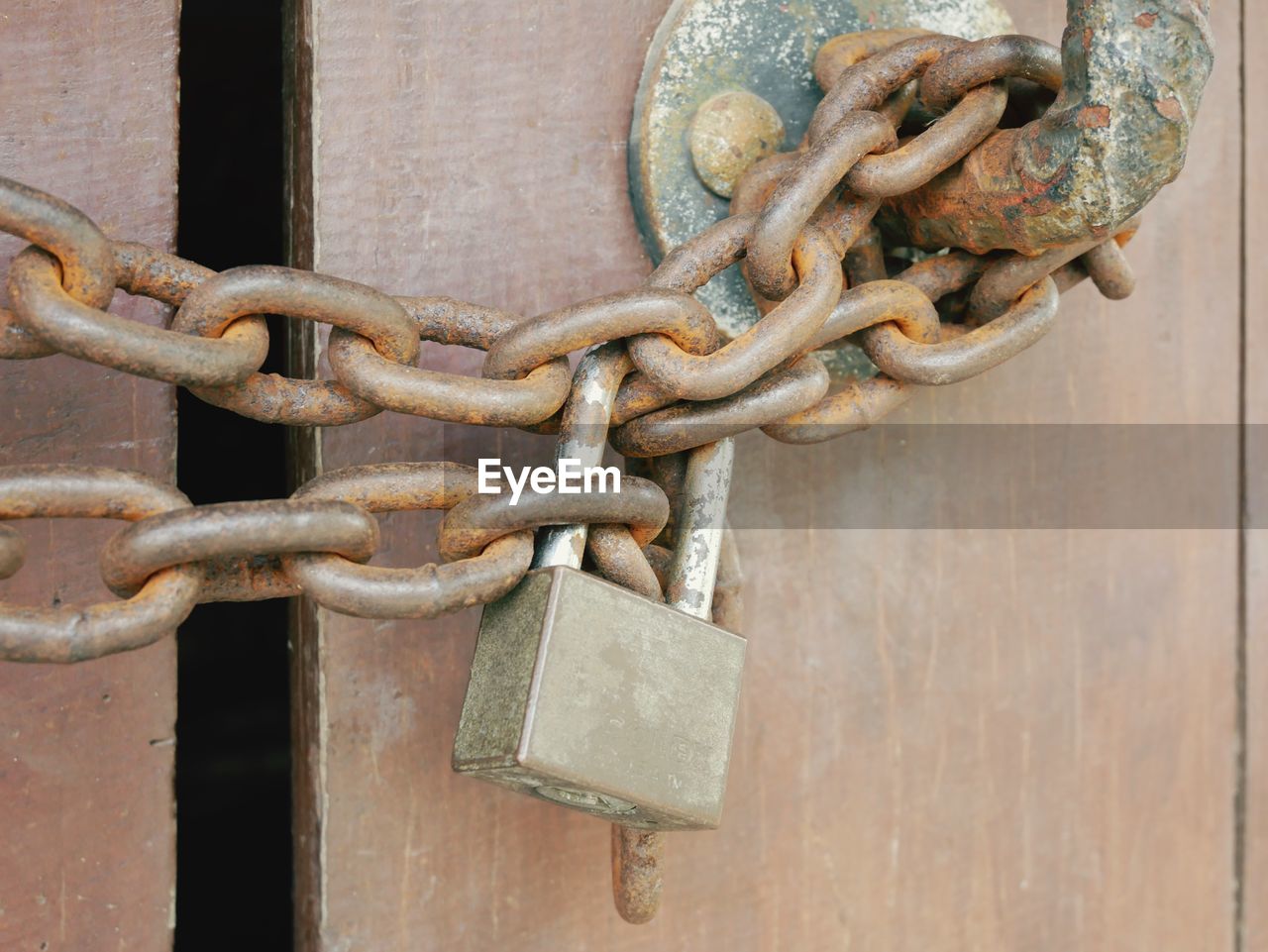 CLOSE-UP OF RUSTY PADLOCK ON METAL