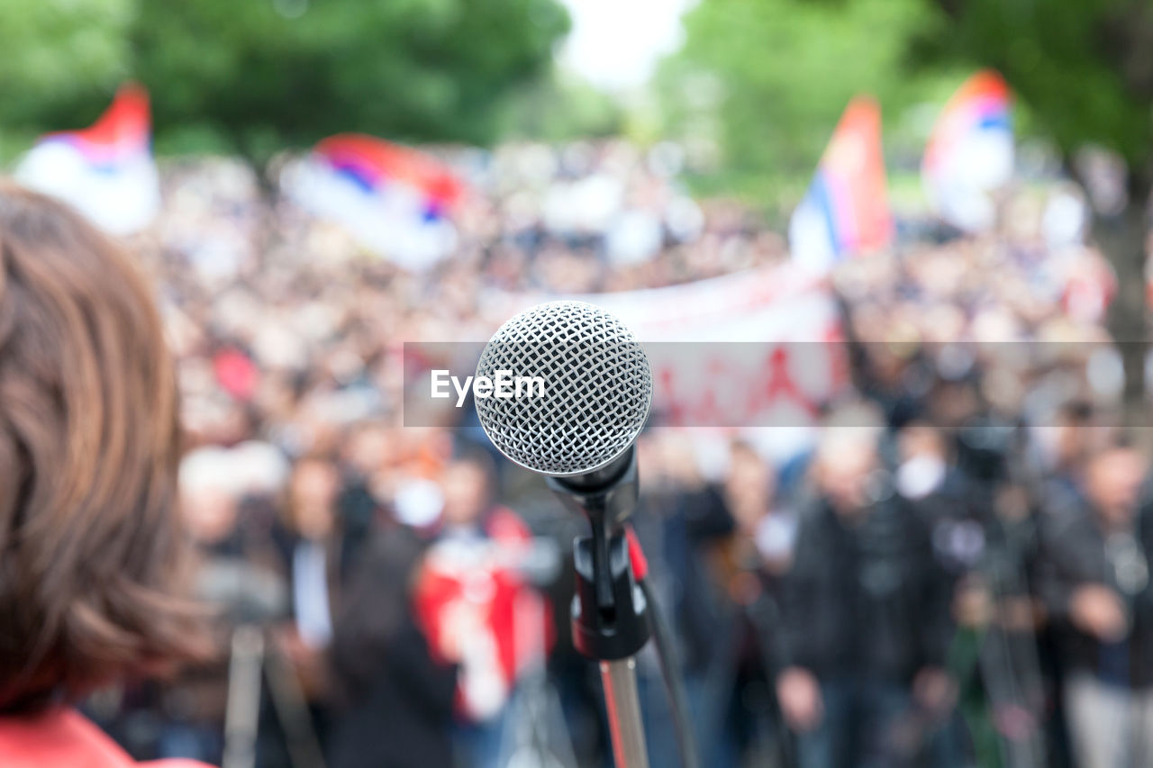 Rear view of woman microphone against audience