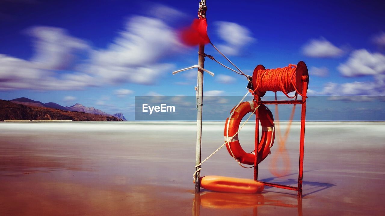 RED FLAG HANGING ON ROPE AGAINST SEA