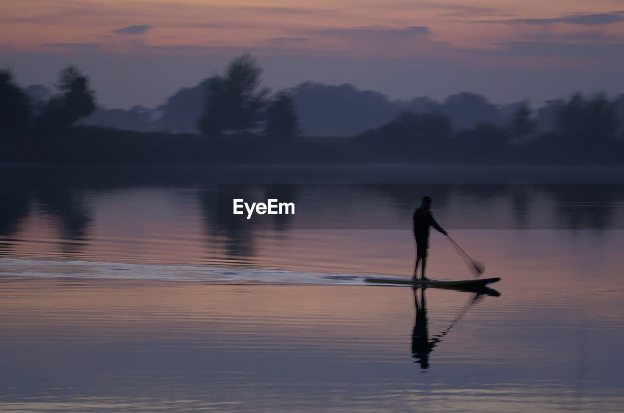 rear view of silhouette man fishing in lake