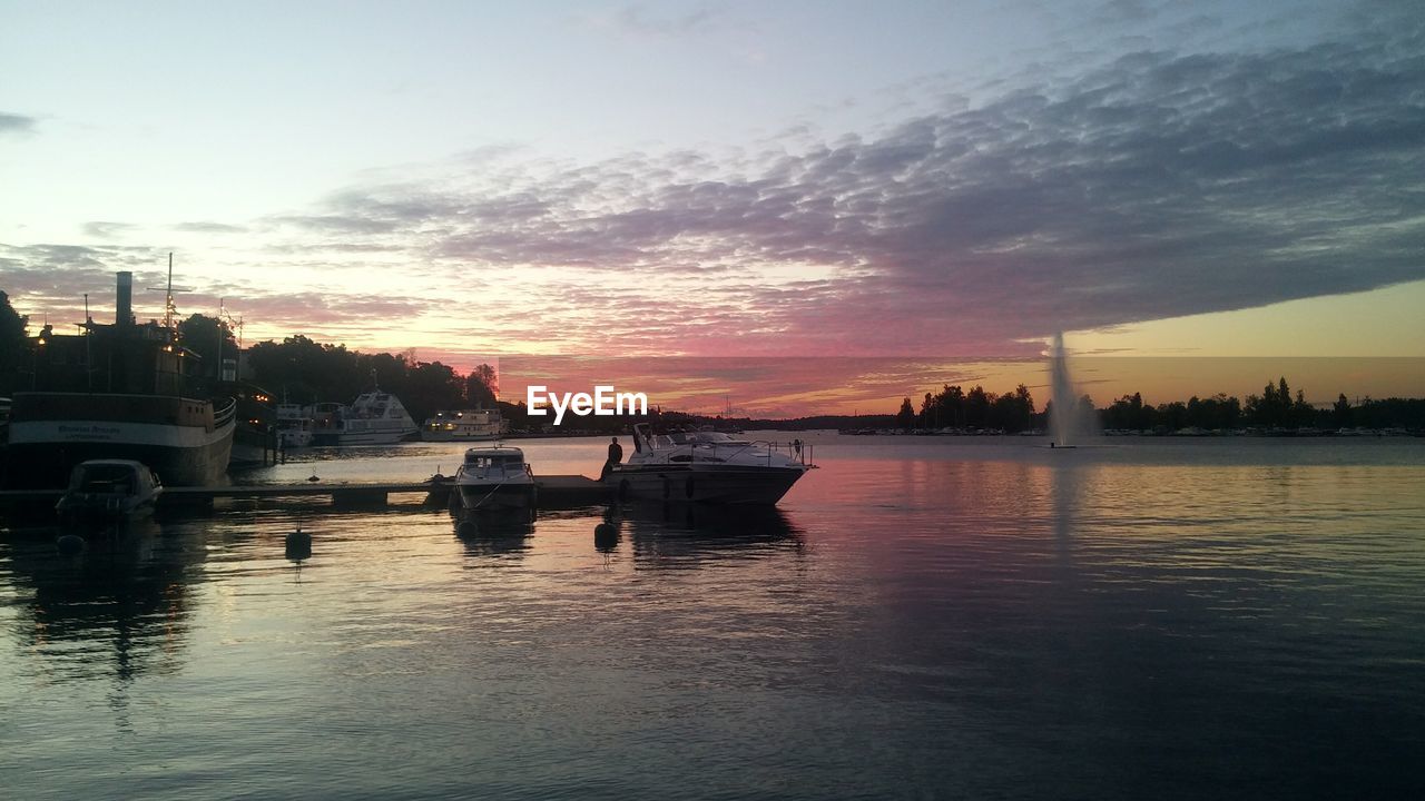 VIEW OF BOATS MOORED IN CITY AT SUNSET