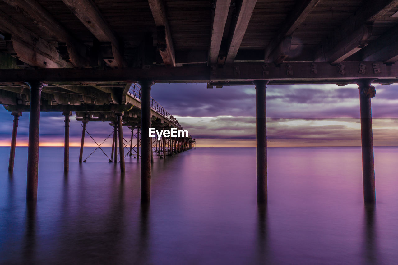 Pier on sea against sky during sunset