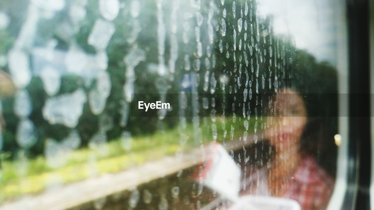 Reflection of woman on wet train window