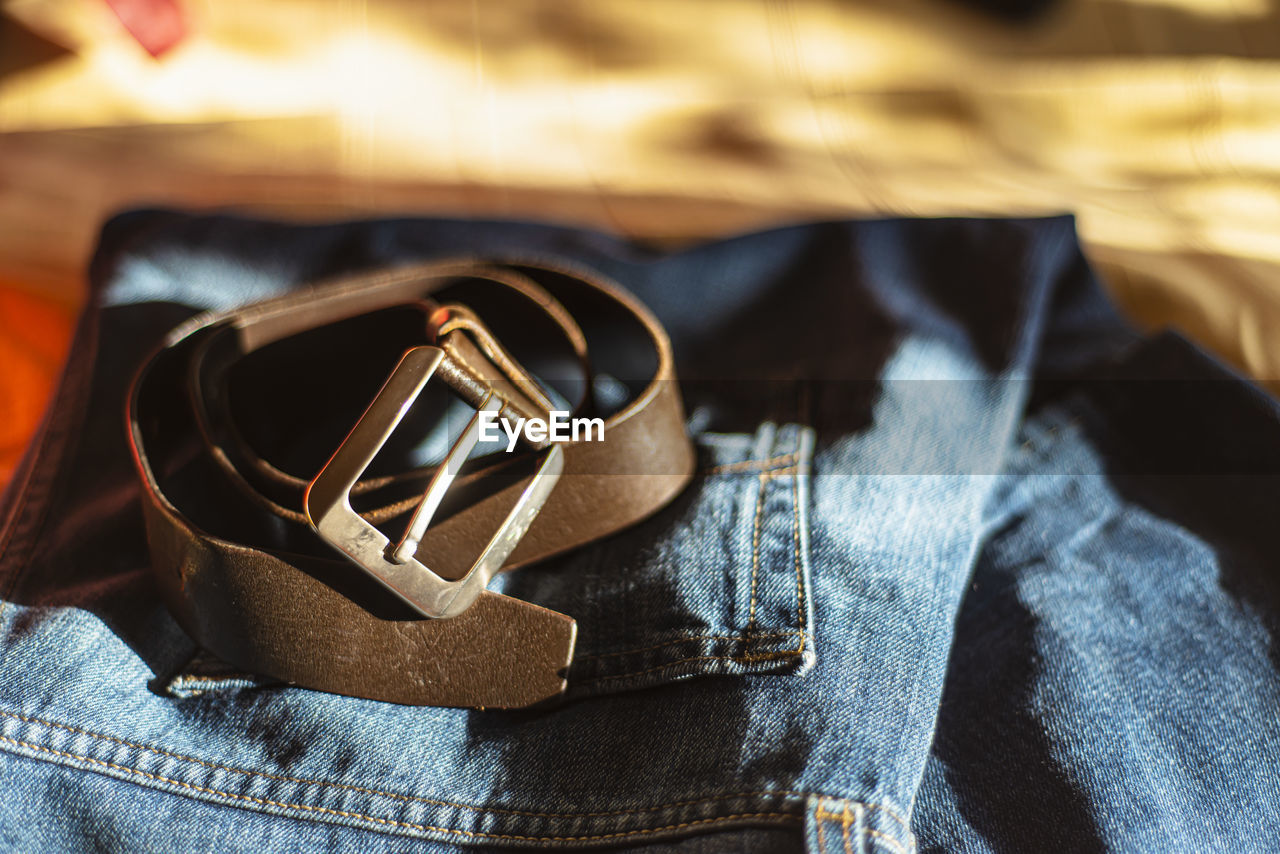 Men's brutal accessories, belt on a dark background with blurred depth of field brown belt and denim