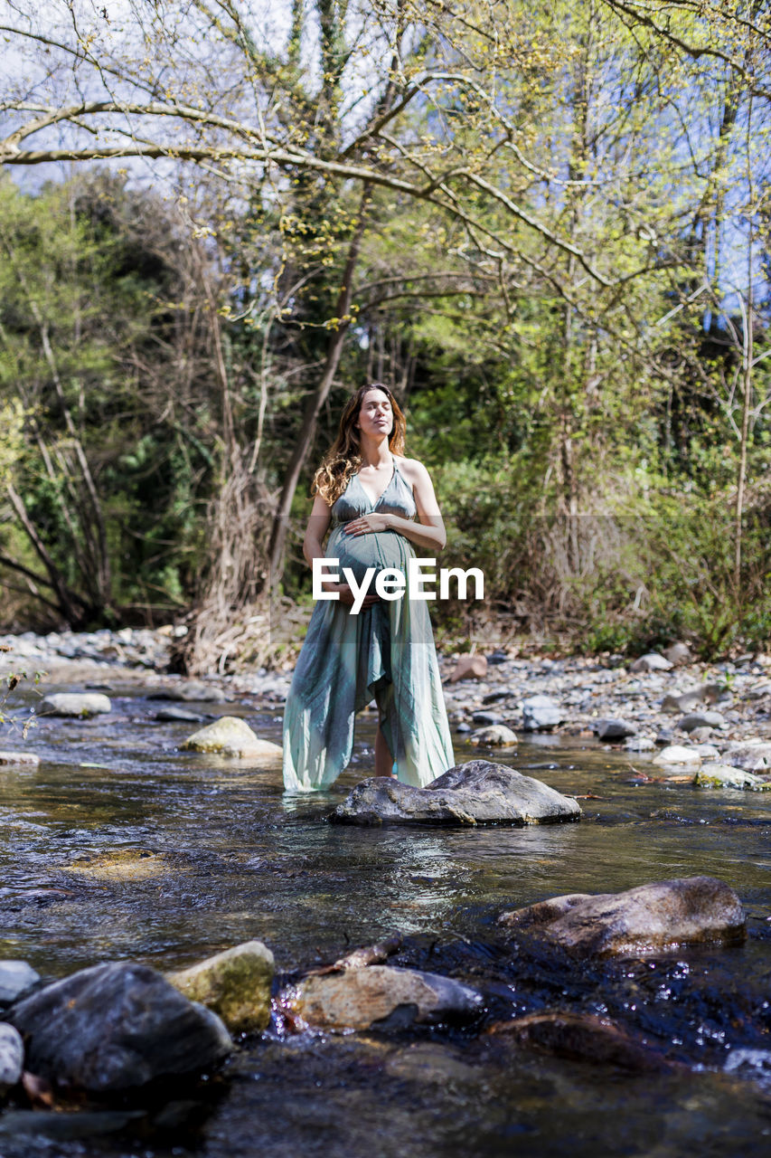 WOMAN STANDING IN FRONT OF A FOREST