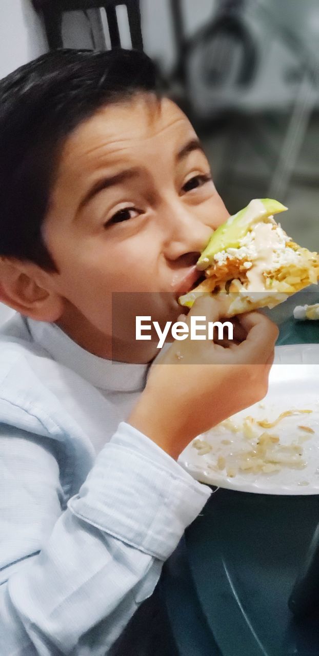 Boy eating food while looking away in restaurant